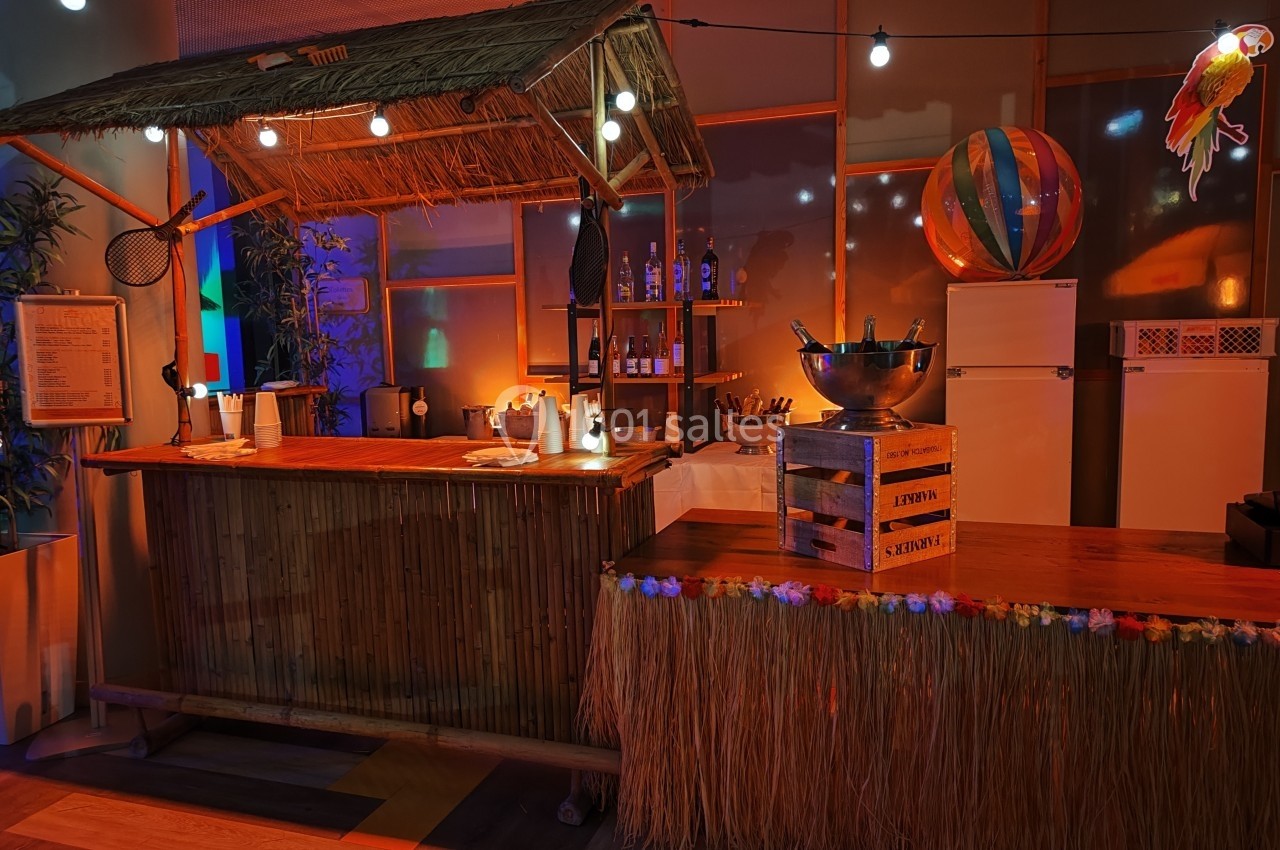 Bar en bambou décoré dans un style tropical, avec guirlandes lumineuses, accessoires exotiques et ambiance chaleureuse.