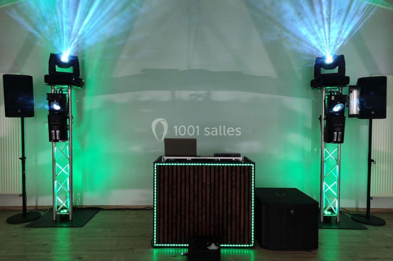 Installation de matériel de sonorisation et d'éclairage avec projecteurs verts, enceintes et table de mixage.