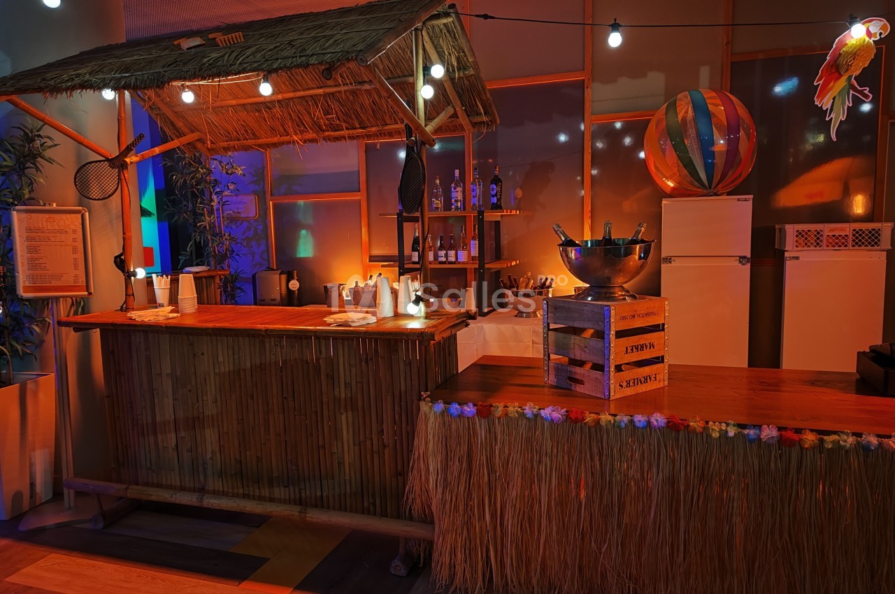 Bar en bambou décoré dans un style tropical, avec guirlandes lumineuses, accessoires exotiques et ambiance chaleureuse.