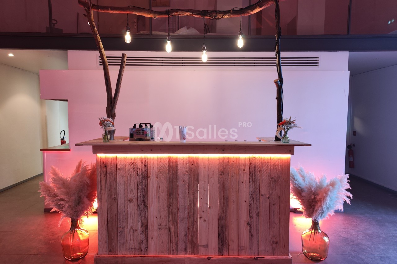 Comptoir en bois décoré de pampas et éclairé par des ampoules suspendues, dans un espace intérieur moderne.