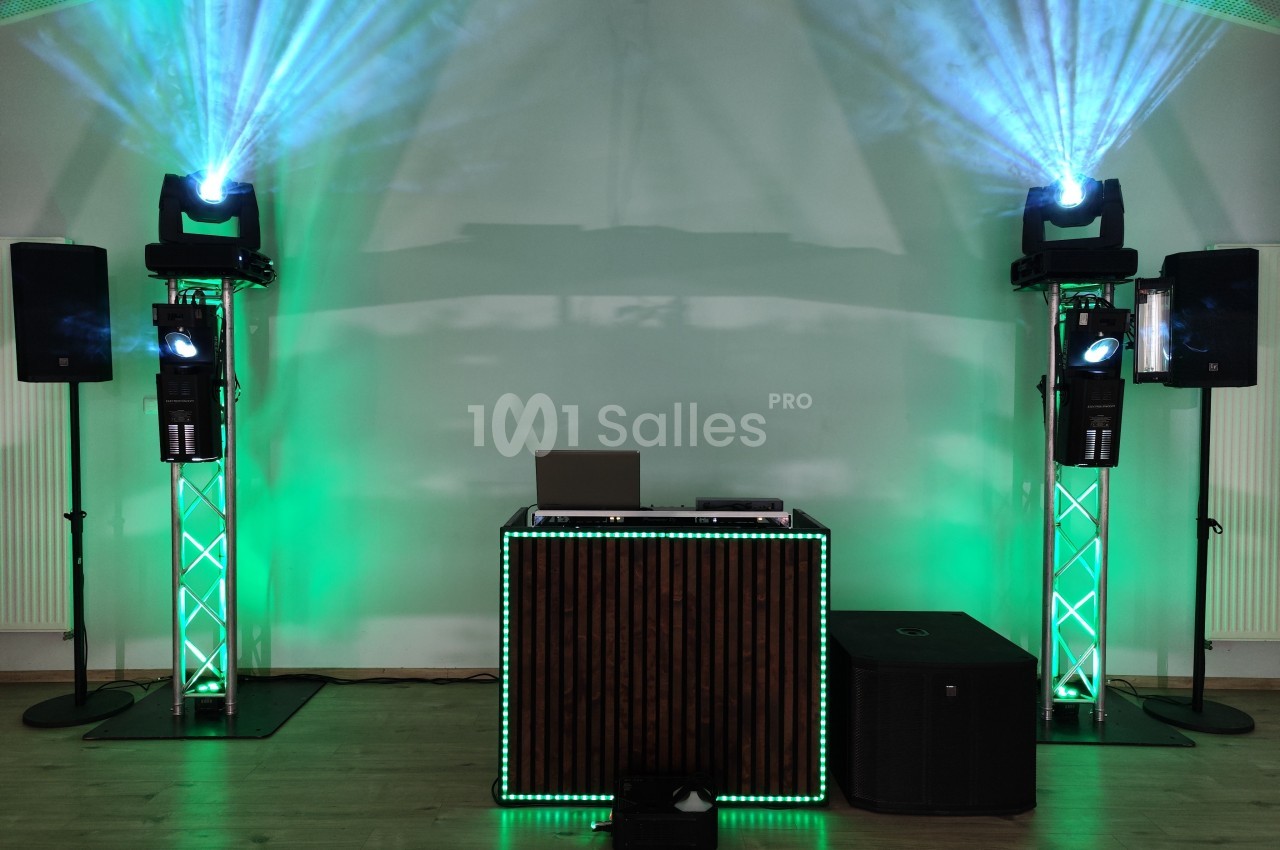 Installation de matériel de sonorisation et d'éclairage avec projecteurs verts, enceintes et table de mixage.