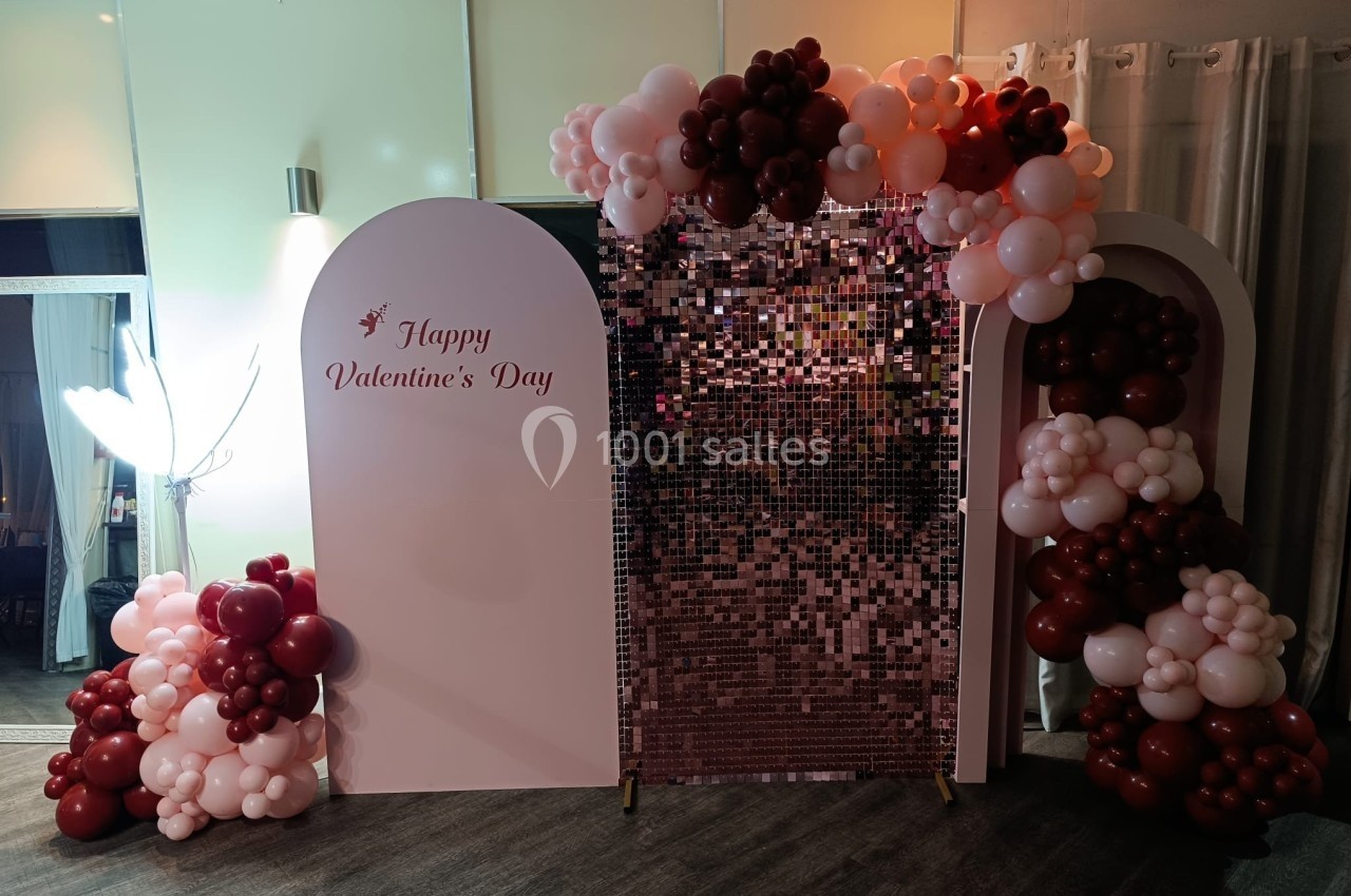 Mur décoratif pour la Saint-Valentin avec ballons rouges et roses entourant un fond scintillant rose.
