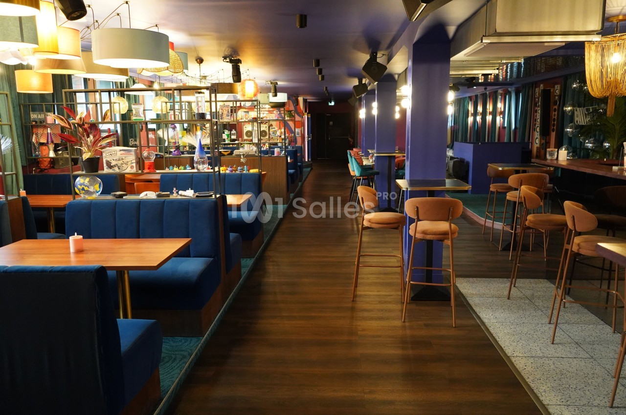 Intérieur d'un restaurant moderne avec banquettes bleues, tables en bois et éclairage chaleureux.