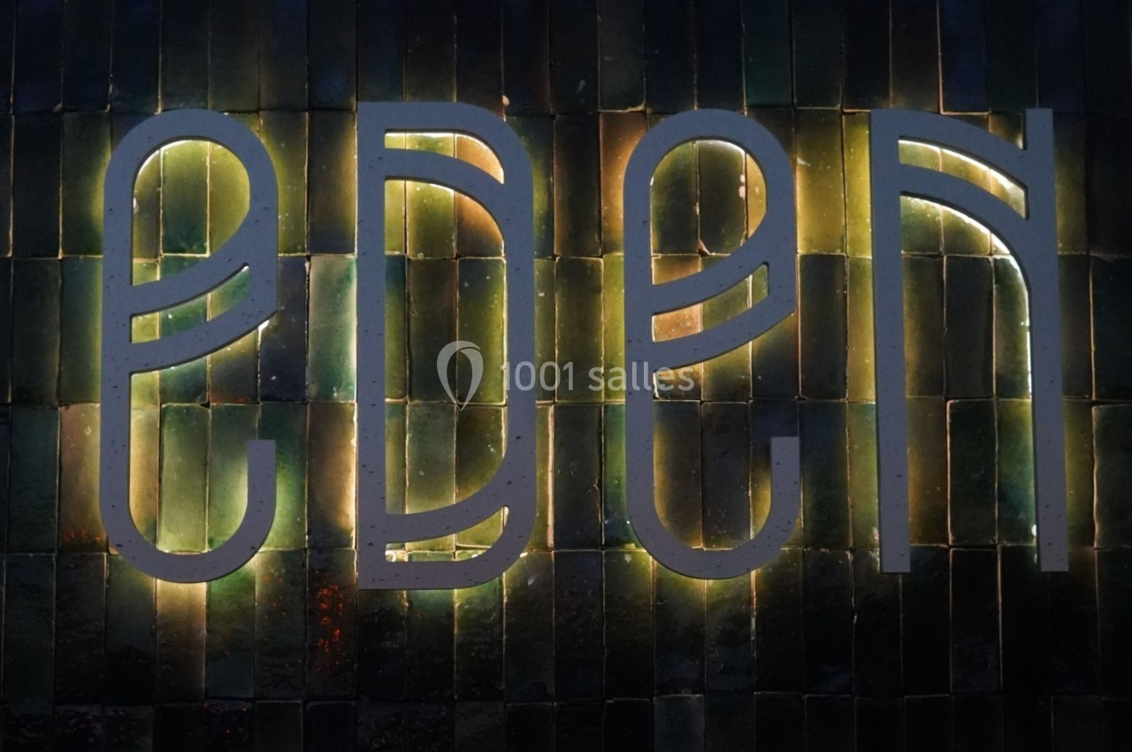 Mur en carreaux sombres avec le mot ’Eden’ écrit en lettres lumineuses modernes.