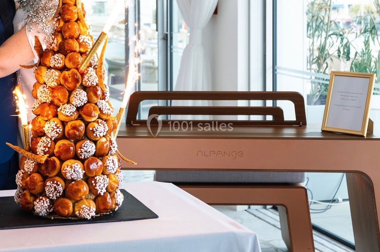 Tour de choux décorée de caramel et de sucre, avec des étincelles, présentée dans une salle lumineuse.