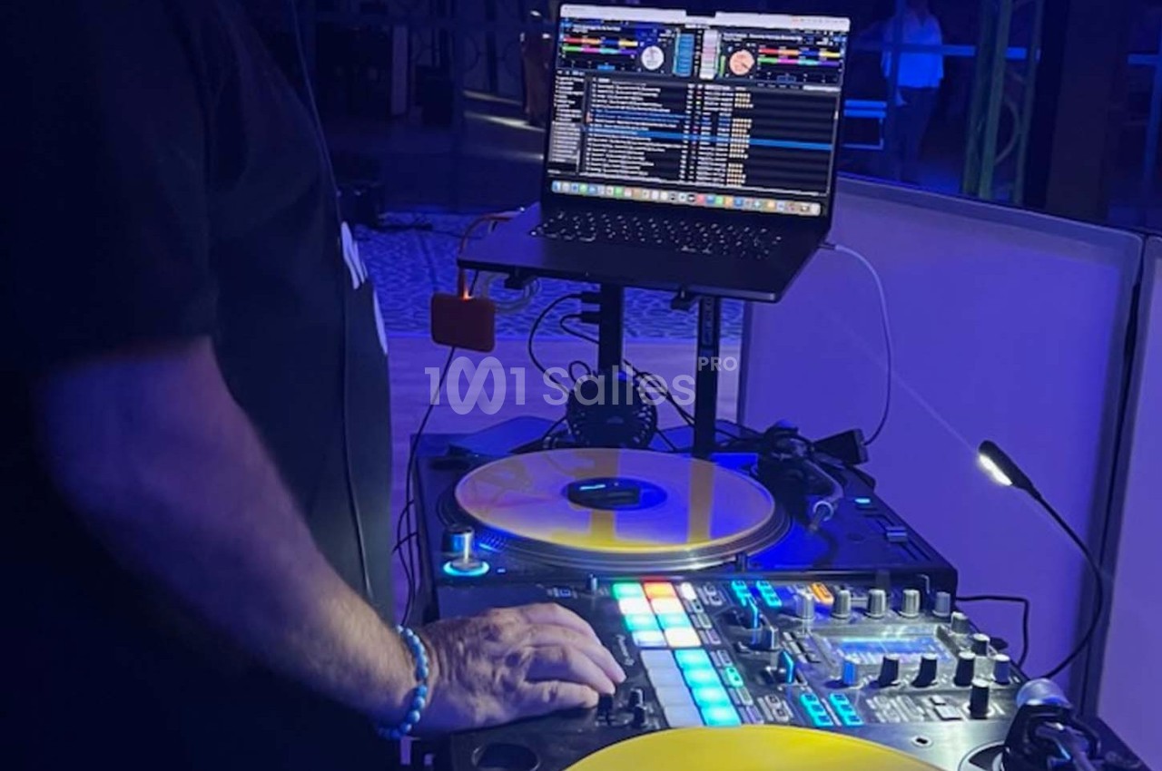 Un DJ mixant de la musique sur une table de mixage avec des vinyles jaunes et un ordinateur portable en arrière-plan.