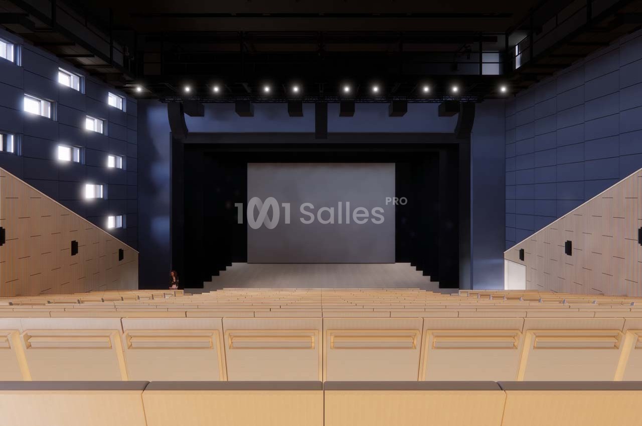 Vue intérieure d'un auditorium moderne avec des sièges en bois clair, une scène vide et un éclairage au plafond.
