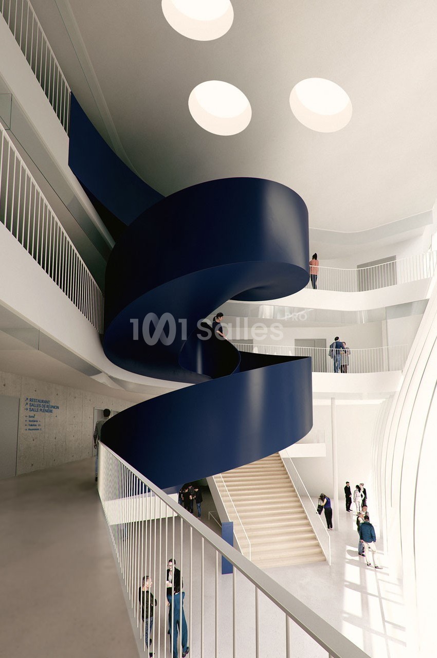 Escalier hélicoïdal bleu au centre d'un bâtiment moderne avec balustrades blanches et puits de lumière circulaires.
