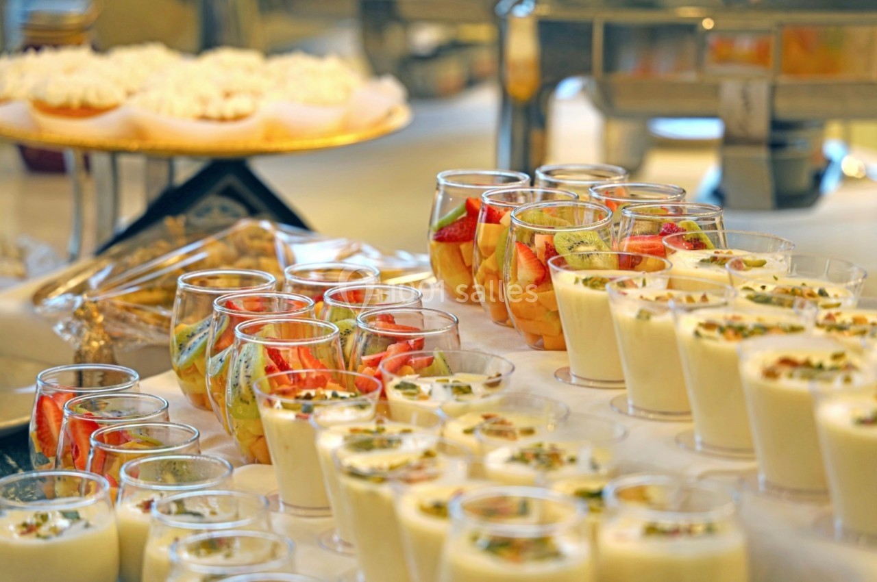 Desserts variés présentés dans des verrines, incluant des mousses, fruits frais et pâtisseries en arrière-plan.