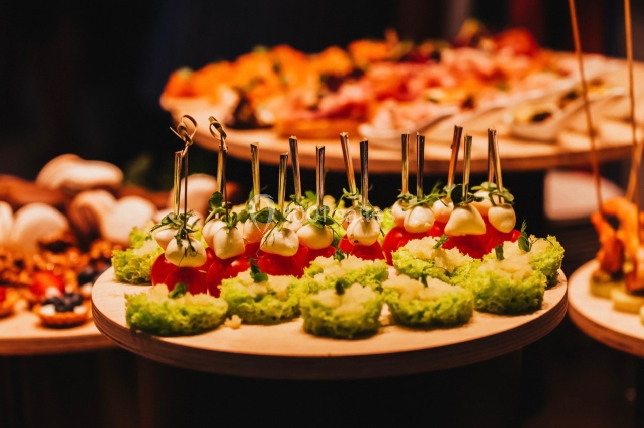 Plateau de bouchées apéritives comprenant des tomates cerises surmontées de crème et des canapés verts.