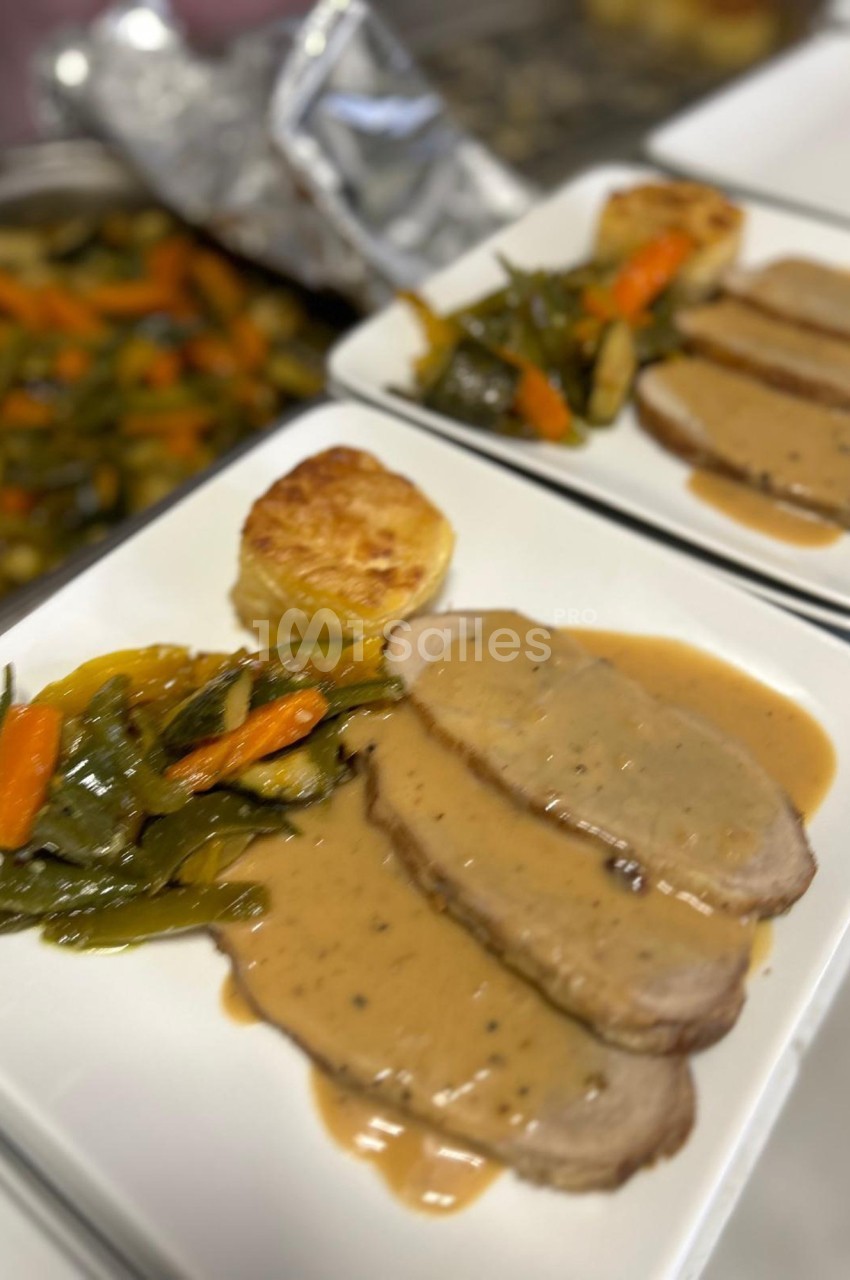 Assiette contenant des tranches de viande nappées de sauce, accompagnées de légumes sautés et d'une pomme de terre gratinée.