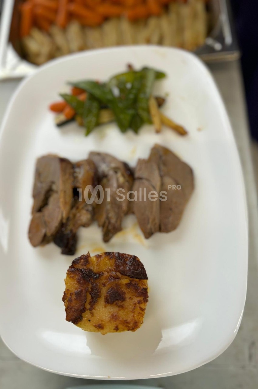 Assiette contenant des tranches de viande, un gratin de pommes de terre et des légumes sautés en accompagnement.