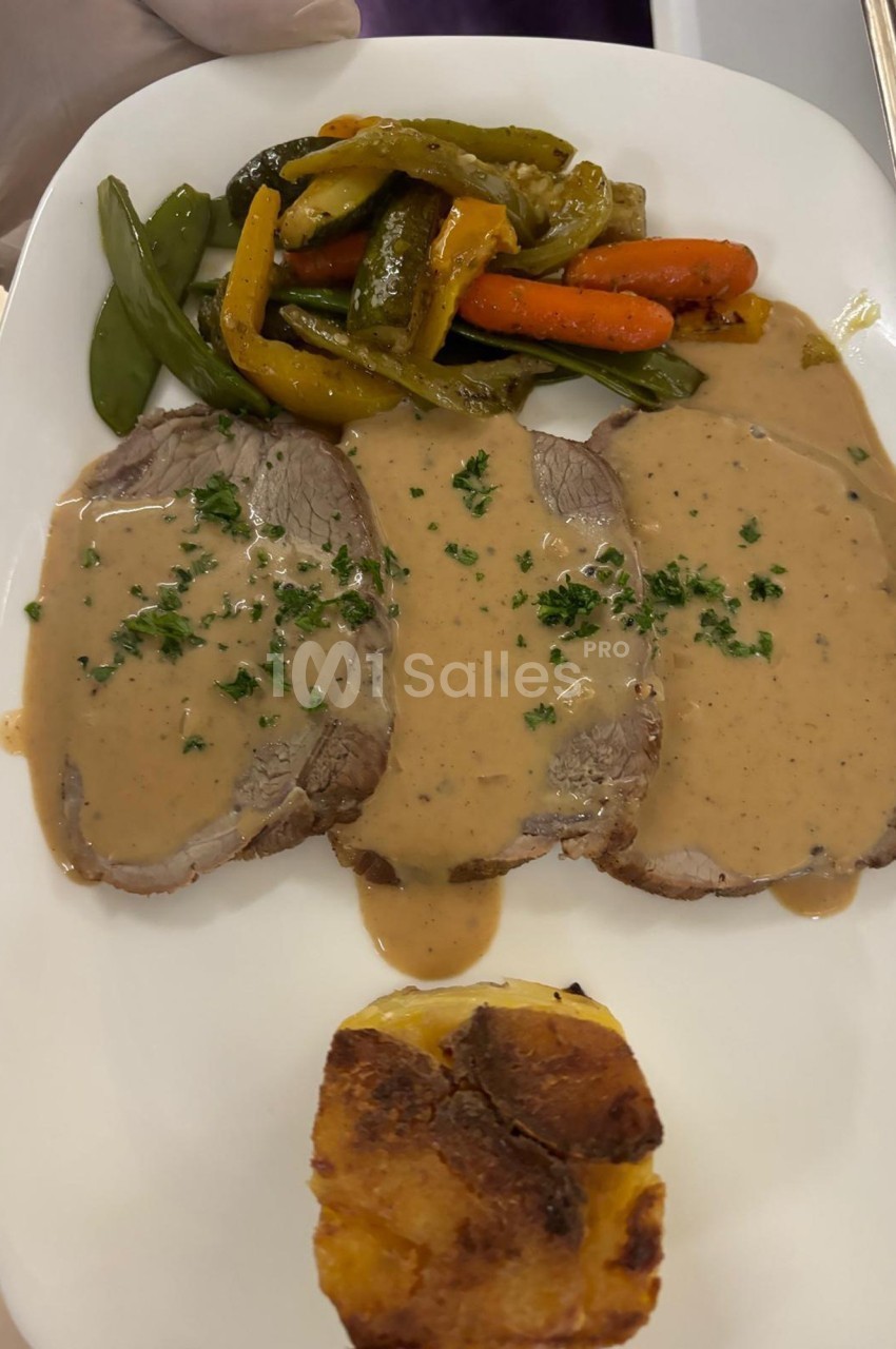 Assiette contenant trois tranches de viande en sauce, légumes sautés et un gratin doré.