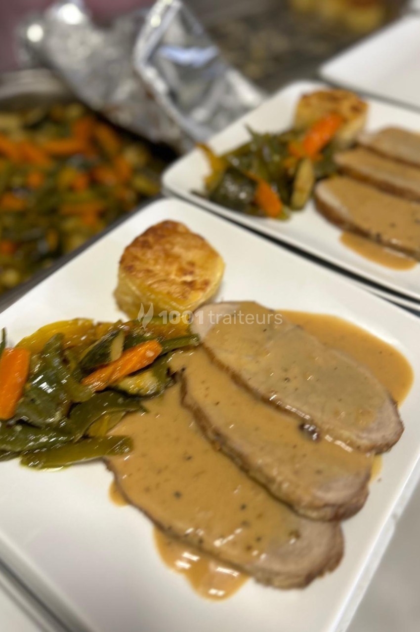 Assiette contenant des tranches de rôti nappées de sauce, accompagnées de légumes sautés et d'une pomme de terre gratinée.