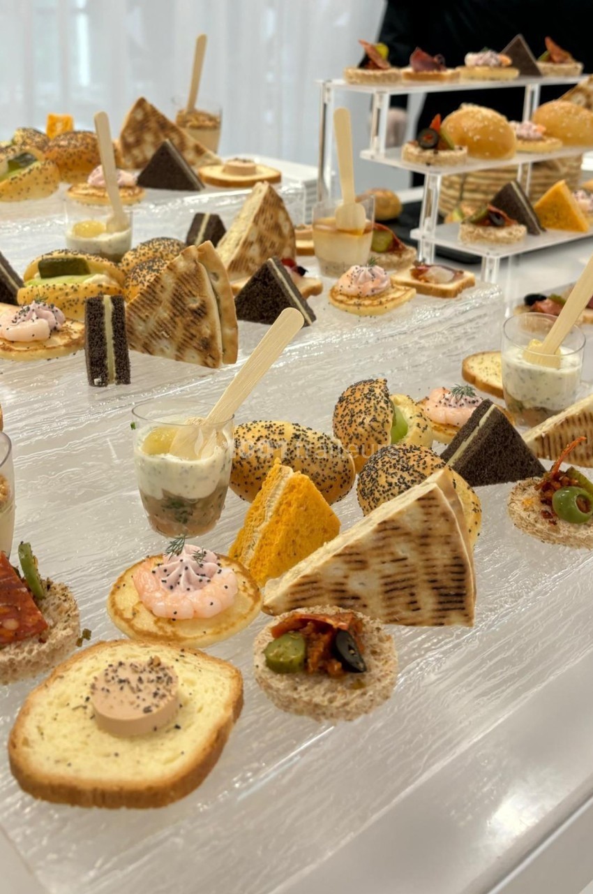 Plateau de bouchées apéritives variées, incluant toasts, verrines, mini-sandwichs et amuse-bouches sur une table blanche.