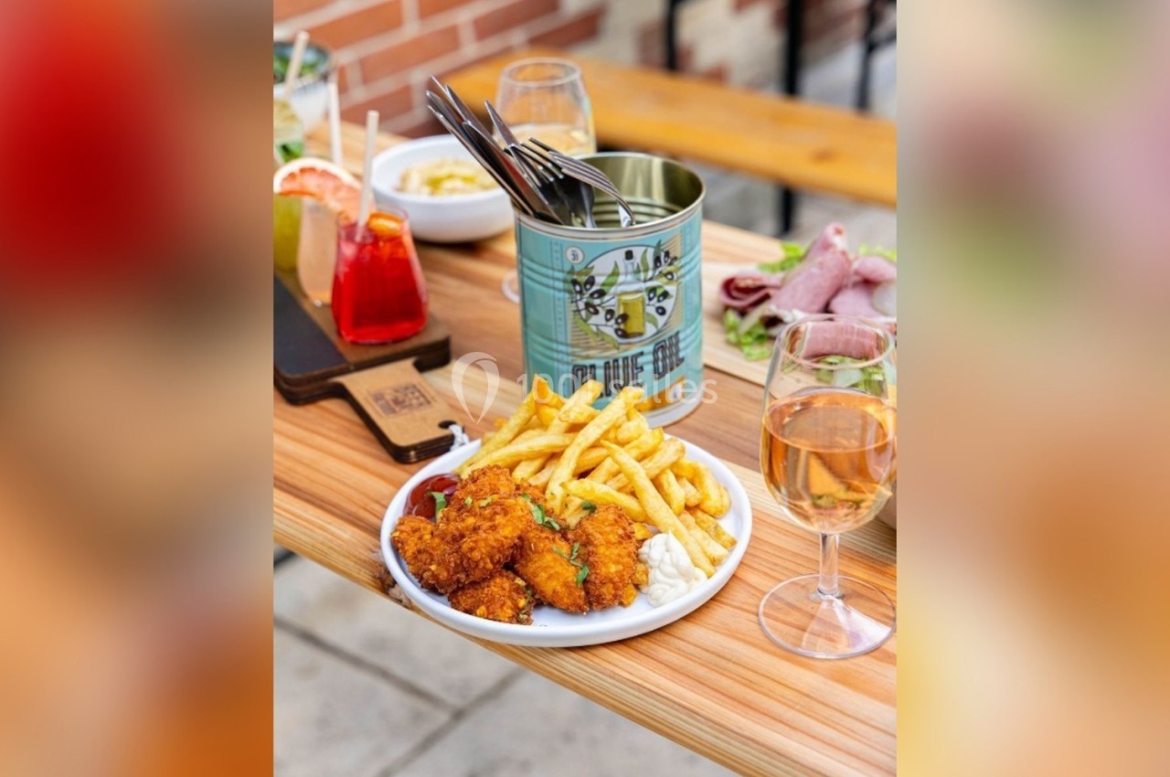Assiette de nuggets et frites sur une table en bois avec boissons et autres plats en arrière-plan.