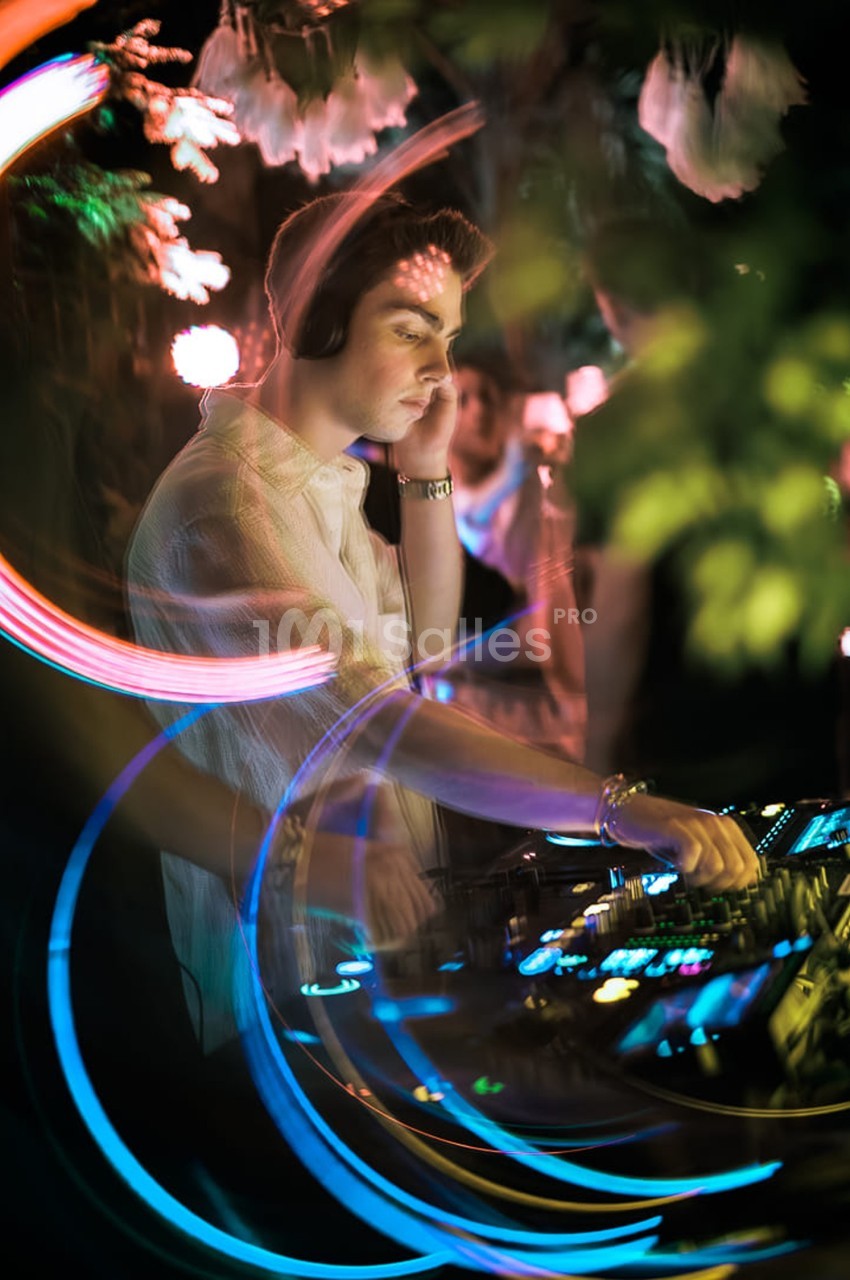 Un DJ mixe de la musique en soirée, entouré de lumières colorées et d'effets lumineux.