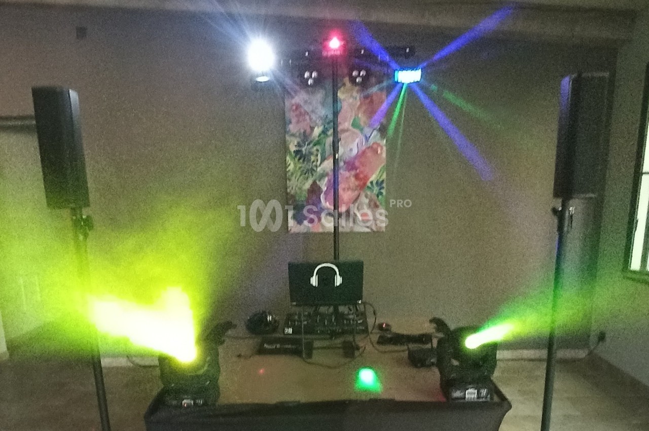 Équipement de sonorisation et éclairage avec projecteurs colorés, enceintes et ordinateur dans une salle.