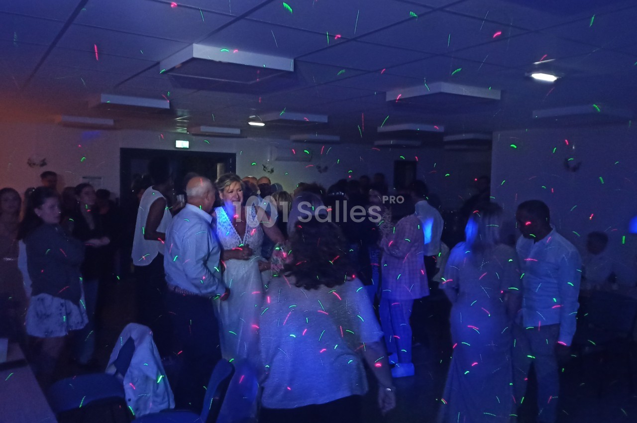 Groupe de personnes dans une salle éclairée par des lumières colorées lors d'une fête ou d'un événement.