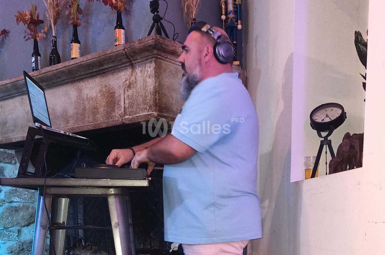 Un DJ portant un casque audio mixe de la musique sur une table équipée d'un ordinateur portable.