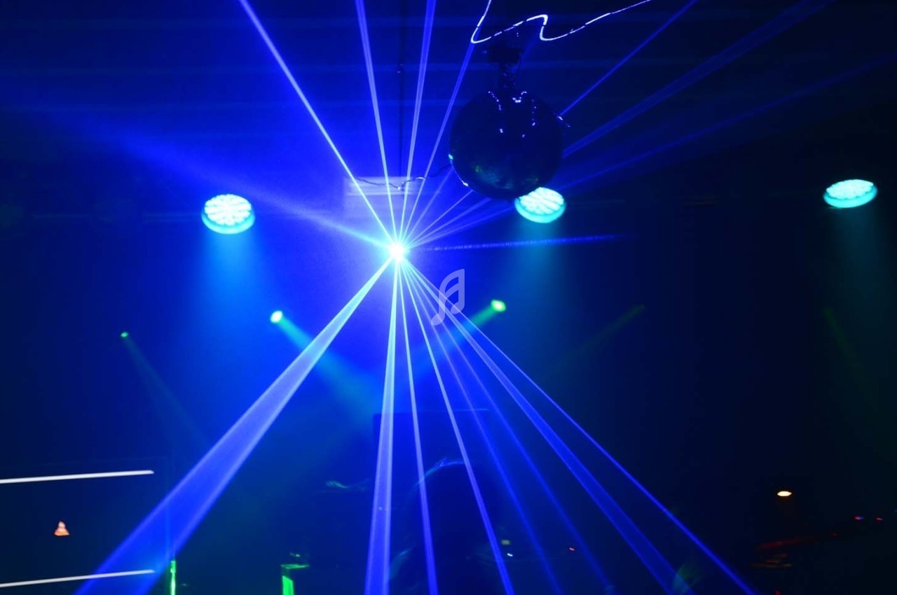 Effets lumineux bleus et verts avec faisceaux laser et projecteurs dans une ambiance de spectacle ou de soirée.