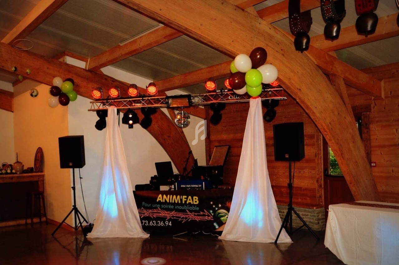 Installation de matériel de sonorisation et éclairage avec des rideaux blancs dans une salle en bois.