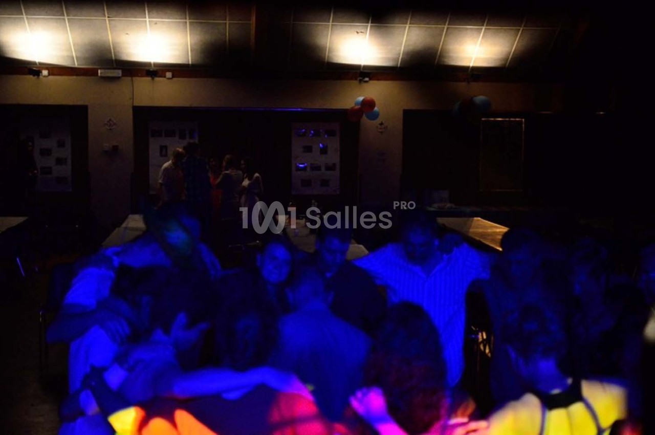 Groupe de personnes dans une salle faiblement éclairée, éclairée par des lumières colorées lors d'un événement festif.