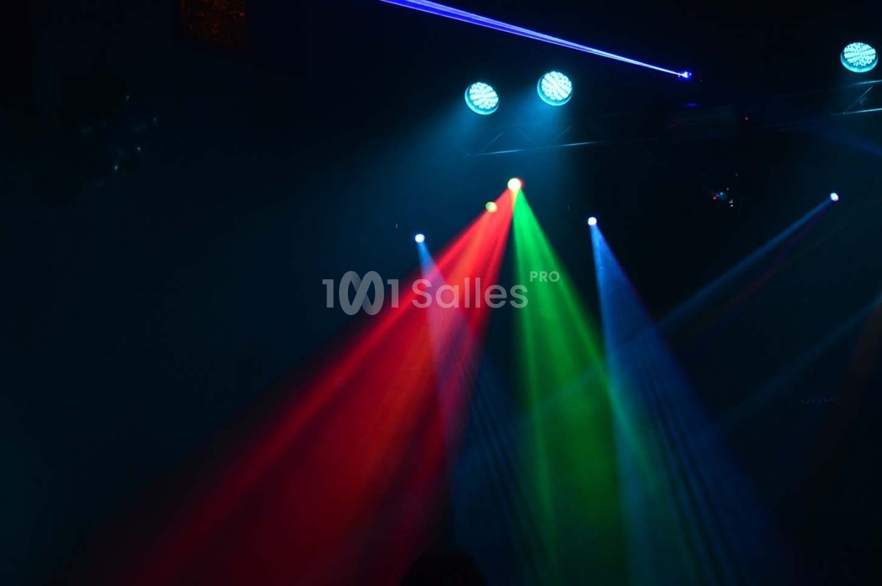 Éclairage de scène avec faisceaux lumineux rouge, vert et bleu sous des projecteurs dans une ambiance sombre.
