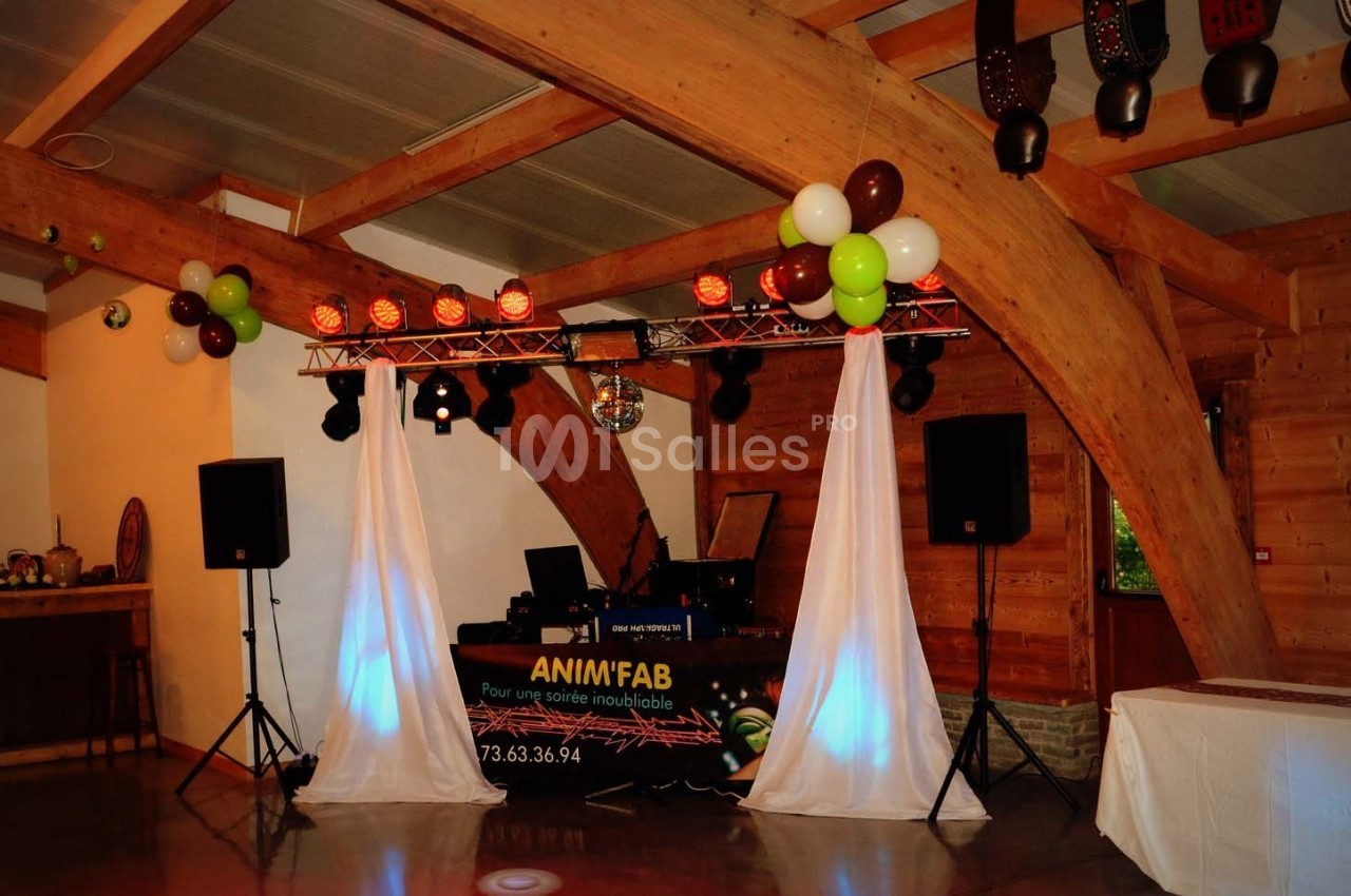 Installation de matériel de sonorisation et d'éclairage pour une soirée dans une salle en bois avec décoration festive.