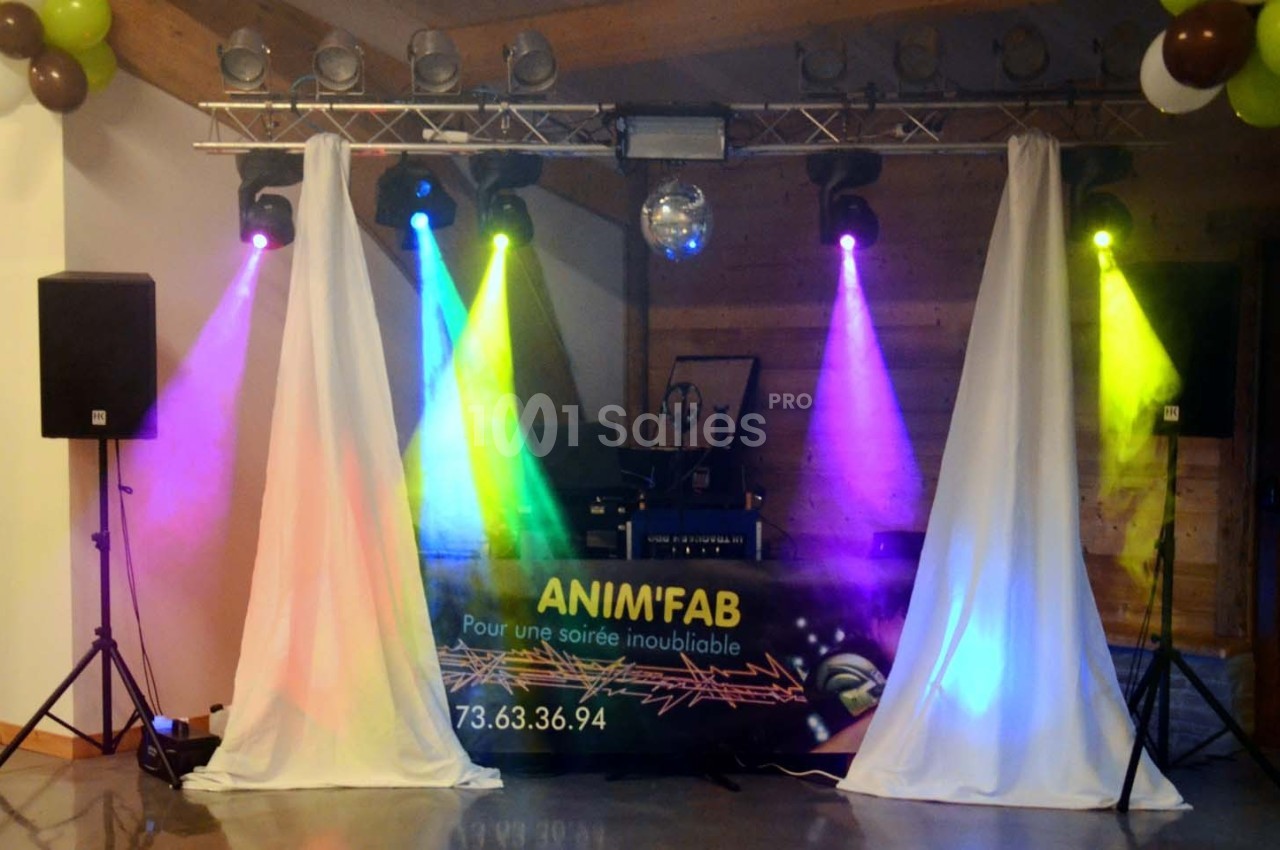 Installation de matériel de sonorisation et éclairage coloré pour une soirée festive en intérieur.