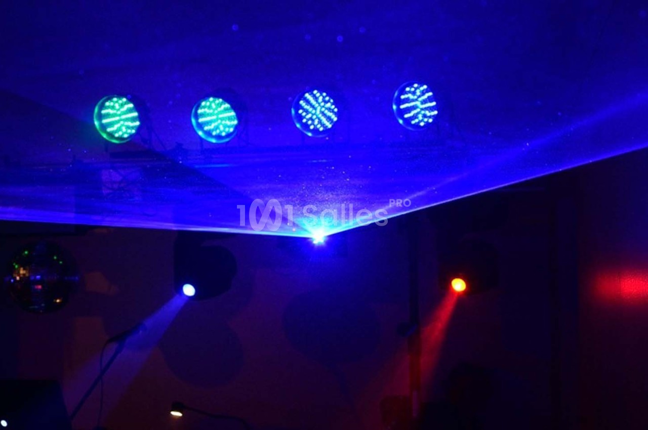 Effets lumineux colorés avec faisceaux laser bleus et spots rouges dans une ambiance sombre.
