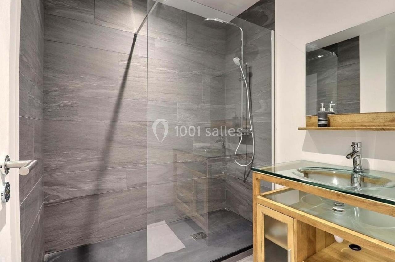 Douche à l'italienne avec paroi en verre, carrelage gris et meuble vasque en bois avec lavabo en verre.