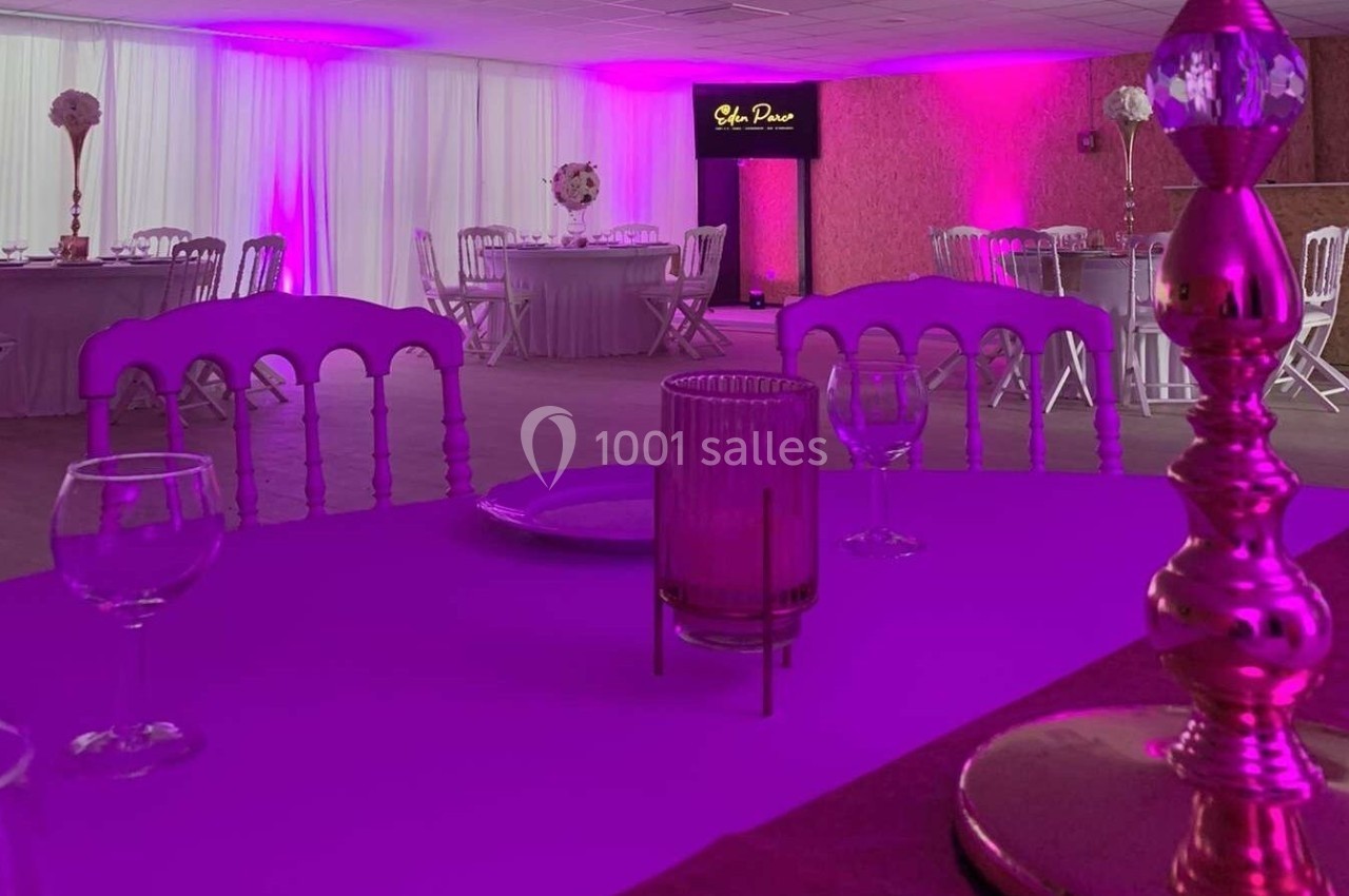 Salle de réception décorée avec des tables dressées, éclairage rose et écran affichant ’Salon Privé’.