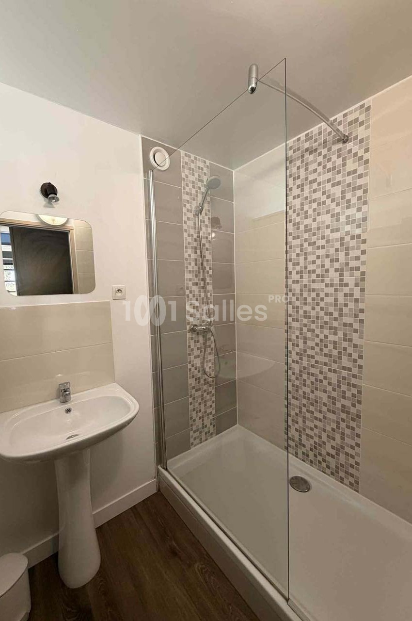 Salle de bain moderne avec douche à l'italienne, paroi vitrée, lavabo sur pied et carrelage mural mosaïque.