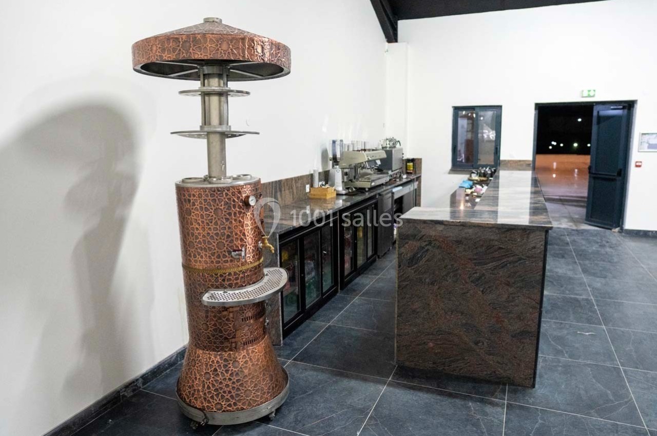Chauffage d'extérieur en métal cuivré placé près d'un comptoir en pierre dans un espace intérieur moderne.