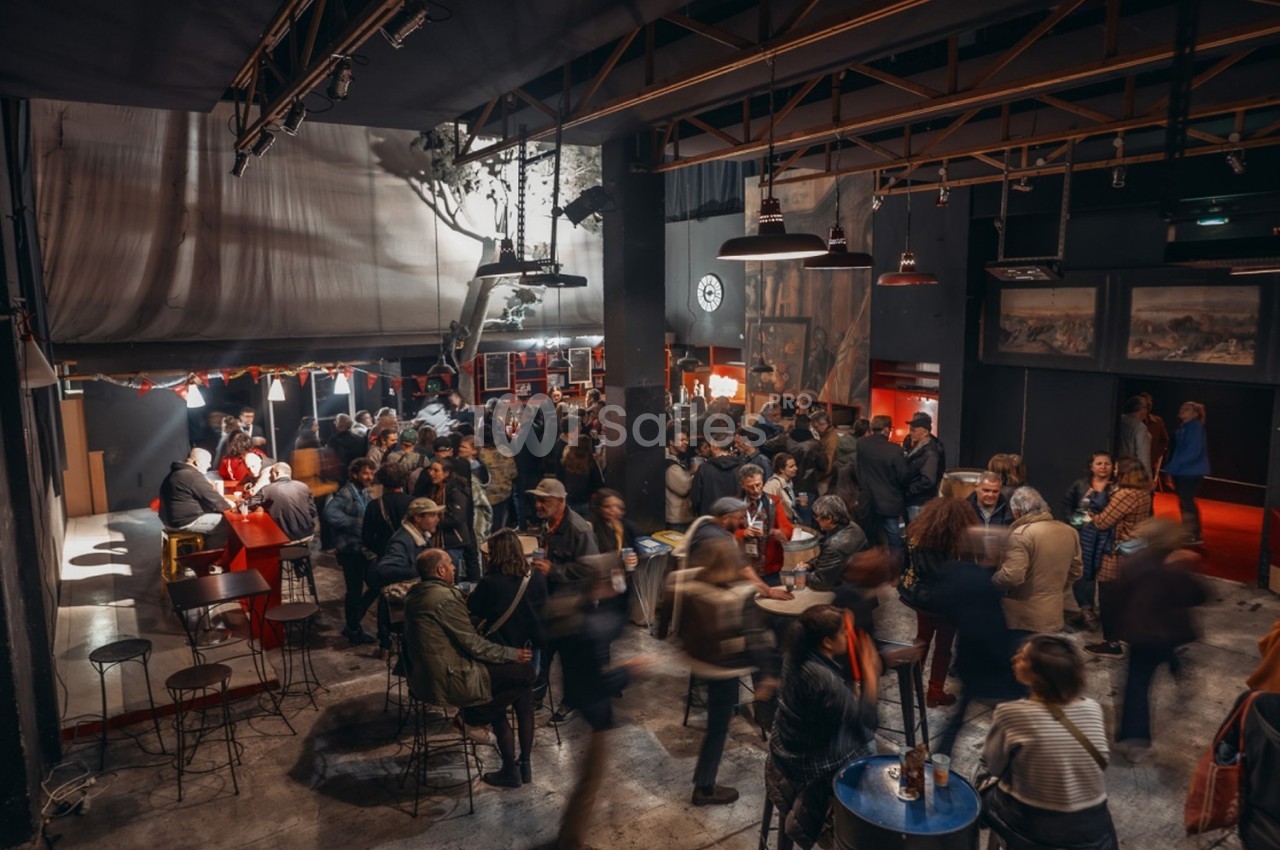 Groupe de personnes rassemblées dans un espace intérieur animé avec des tables, un bar et une lumière tamisée.