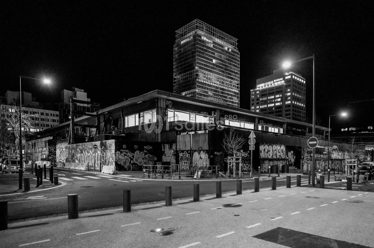 Bâtiment urbain recouvert de graffitis, entouré de rues désertes et éclairé par des lampadaires la nuit.