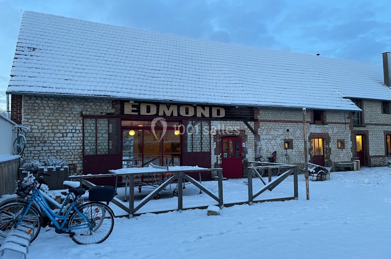 Bâtiment en pierre avec toit enneigé, enseigne ’Edmond’, vélos stationnés devant et lumière émanant des fenêtres.