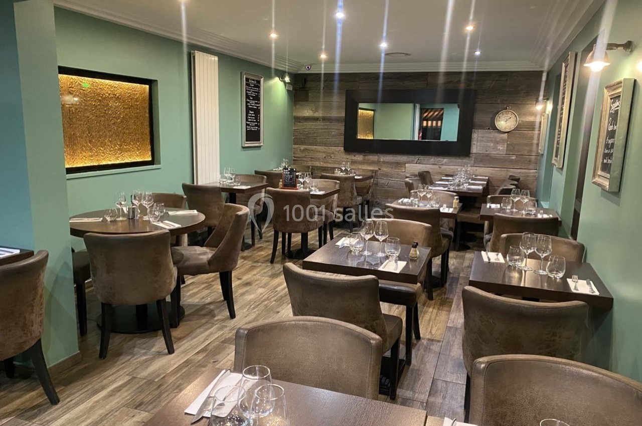 Salle de restaurant élégante avec tables dressées, chaises en velours marron et éclairage chaleureux.