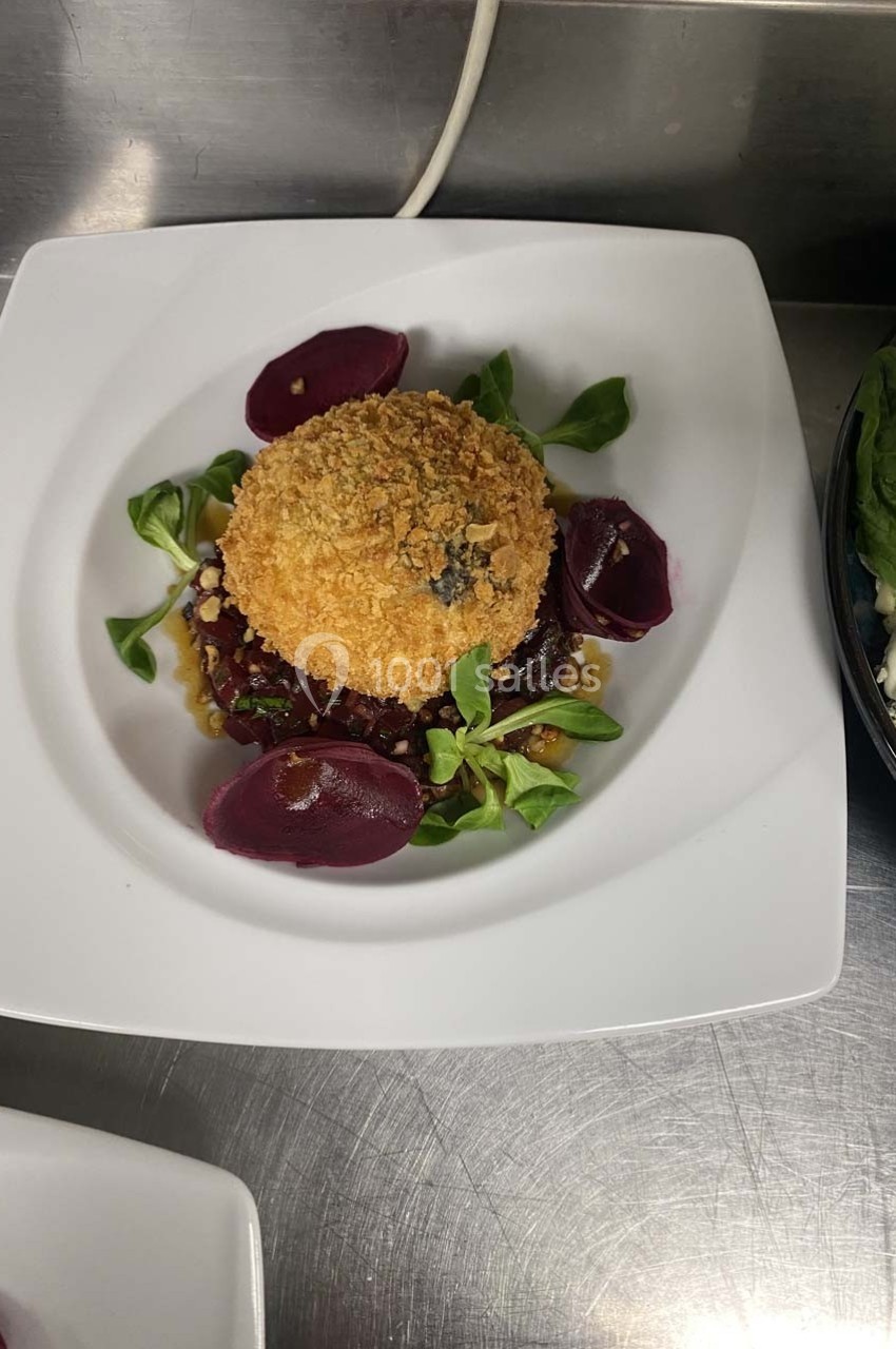 Plat dressé sur une assiette blanche, composé d'un aliment pané, de betteraves, de mâche et de noix.