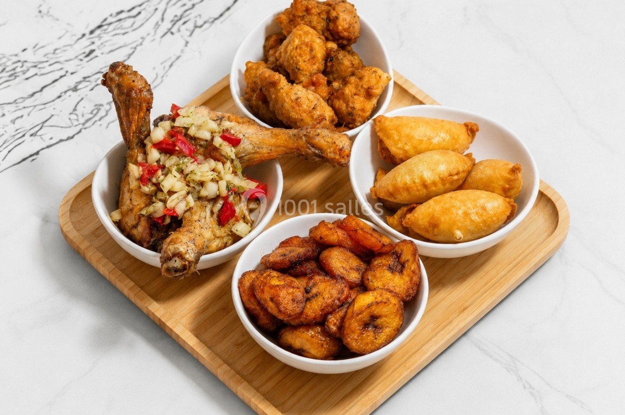 Plateau en bois avec quatre bols contenant du poulet frit, des beignets, des empanadas et des bananes plantains grillées.