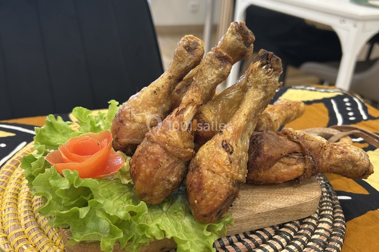 Pilons de poulet rôtis disposés sur un lit de laitue avec une décoration en forme de rose en tomate.
