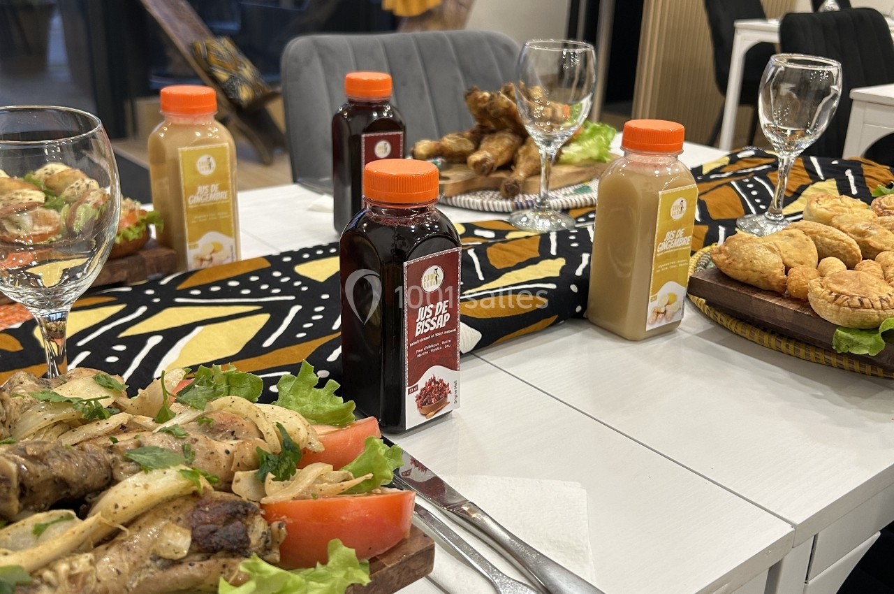 Repas servi sur une table avec boissons, plats de viande, légumes, feuilletés et décoration colorée.