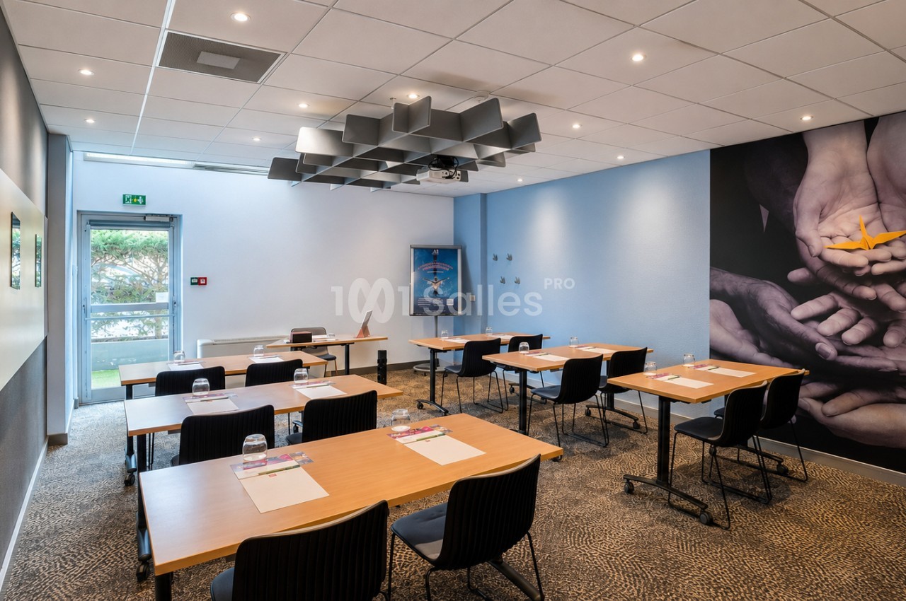 Salle de réunion avec tables en bois, chaises noires et accès direct à l'extérieur.