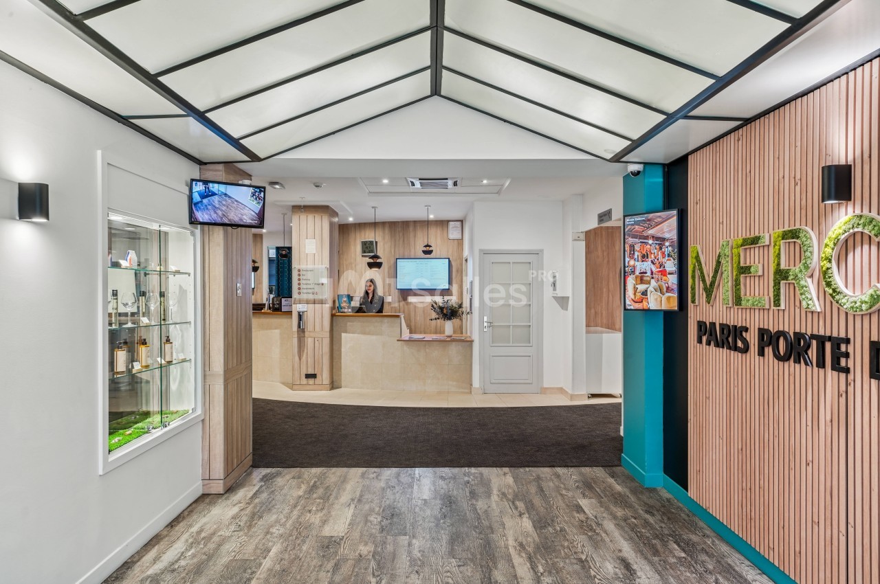 Hall d'entrée moderne avec comptoir de réception, sol en bois, murs décorés et éclairage contemporain.