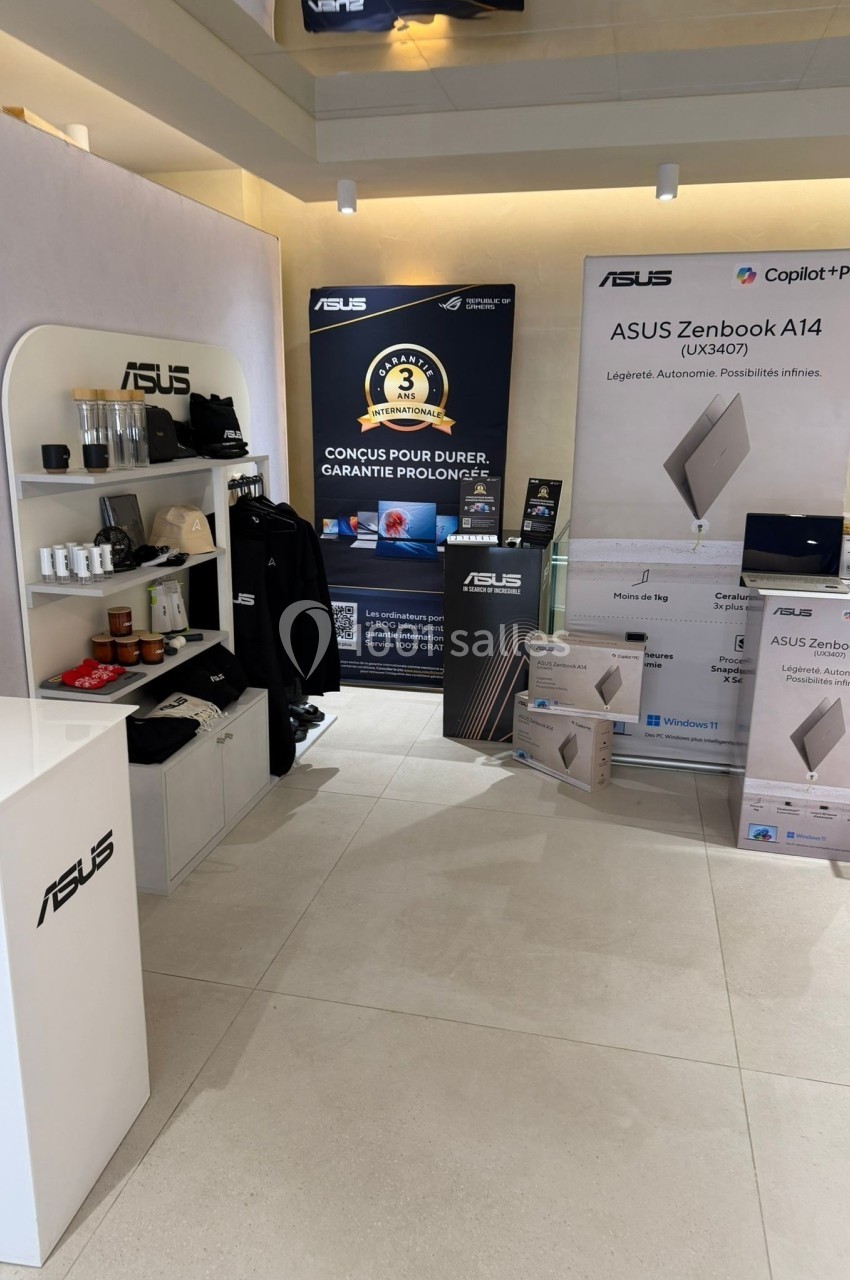 Stand présentant des produits ASUS, avec ordinateurs portables, accessoires, affiches promotionnelles et étagères d…