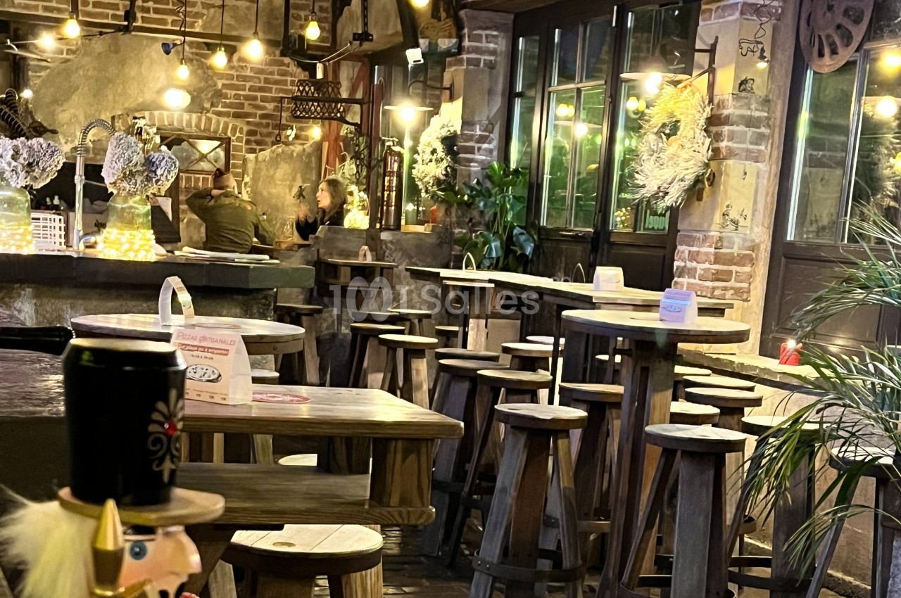 Intérieur d'un café chaleureux avec des tables en bois, des lumières suspendues et une décoration rustique.