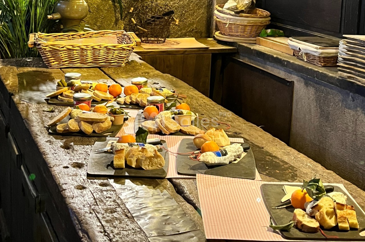 Plateaux de dégustation avec fromages, fruits, pain et condiments disposés sur une table en bois rustique.