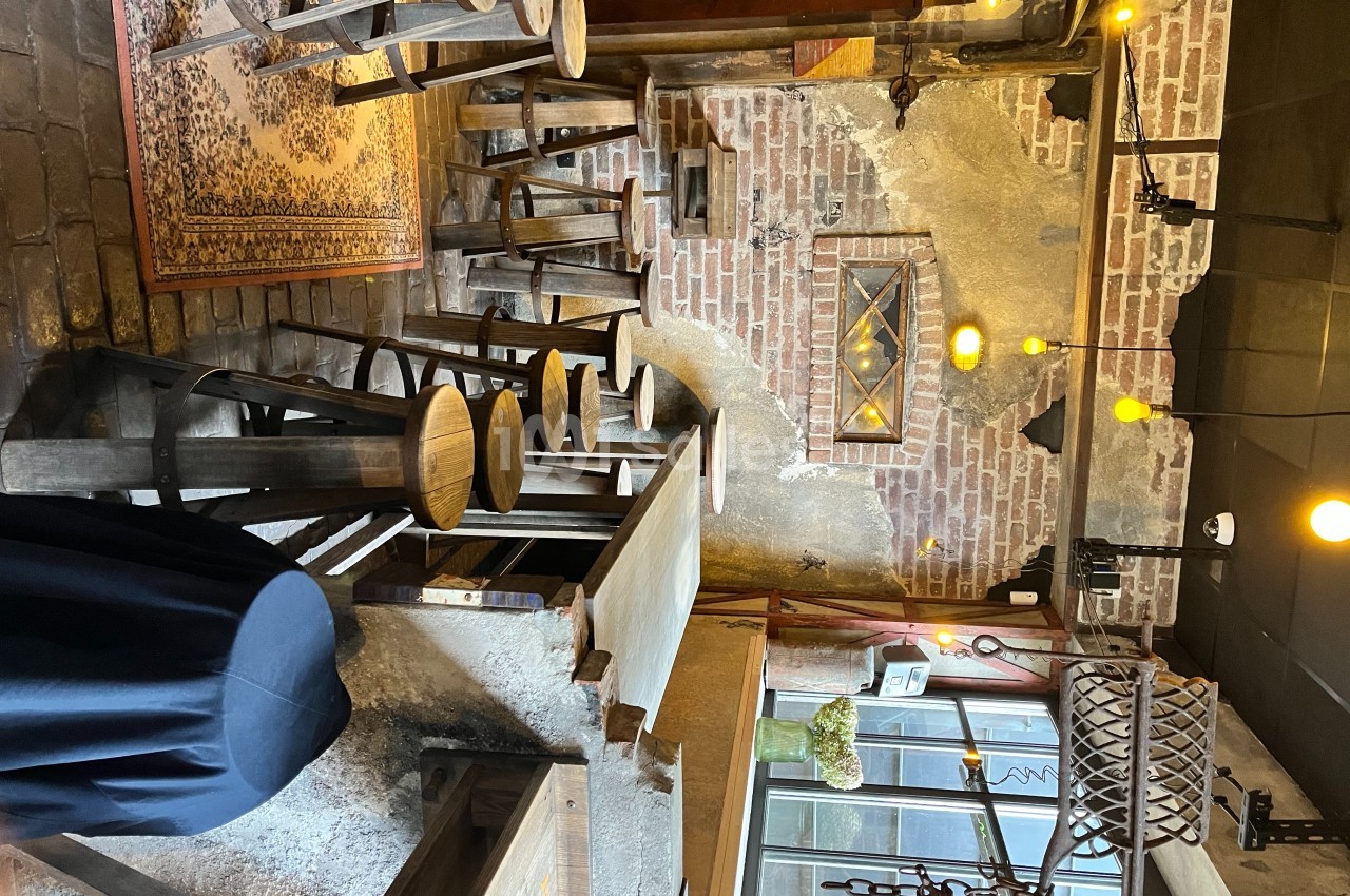 Intérieur d'un café rustique avec murs en briques, tabourets en bois, éclairage chaleureux et décorations vintage.