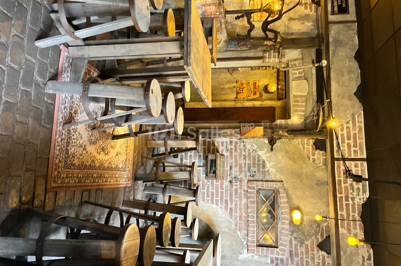 Salle rustique avec murs en briques, mobilier en bois brut, tapis au sol et éclairage chaleureux suspendu.